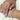 Close-up of hands wearing rings and a bracelet on a light background
