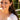 Woman wearing a gold necklace and earrings with a blurred outdoor background