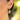 Gold hoop earring with strawberry-shaped charm worn by a person.