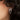 Earring with bow design worn by a person with dark hair.