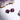 Purple heart-shaped stud earrings on a white surface with a crystal rock in the background
