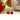 Red gemstone stud earrings on a light surface with a strawberry and blurred background