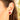 Close-up of an ear wearing a red earring with a blurred background