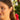 Close-up of a woman wearing red earrings with a blurred floral background