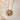 Gold sunflower-shaped necklace with a butterfly and honeycomb design on a textured beige background