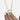 Gold necklace with heart-shaped charms held by a hand on a white background