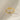 Gold bow-shaped ring on a beige fabric background